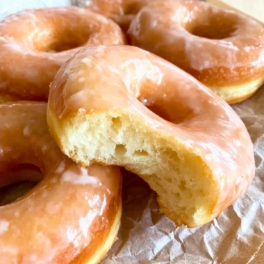 Freshly glazed sourdough donuts on a wooden table