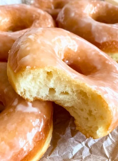 Freshly glazed sourdough donuts on a wooden table