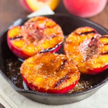Grilled peaches sprinkled with cinnamon and brown sugar on a plate