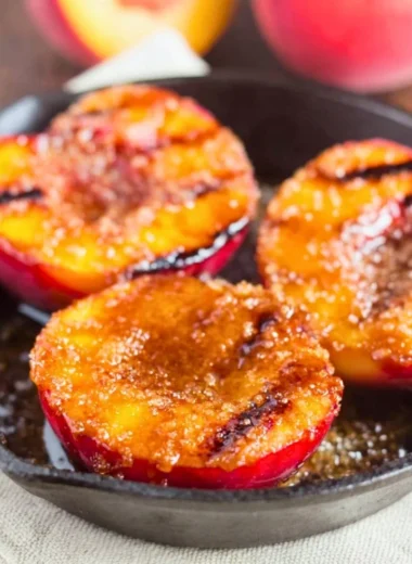 Grilled peaches sprinkled with cinnamon and brown sugar on a plate