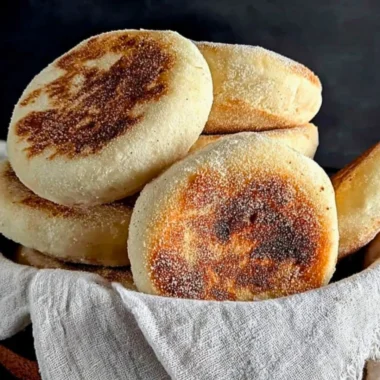 Freshly baked homemade sourdough English muffins on a wooden table.