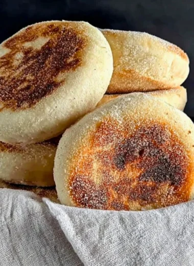 Freshly baked homemade sourdough English muffins on a wooden table.
