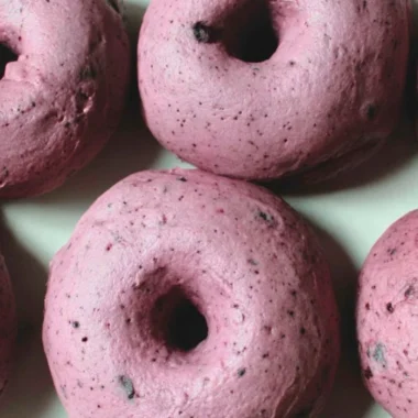 Freshly baked sourdough blueberry bagels on a wooden board.