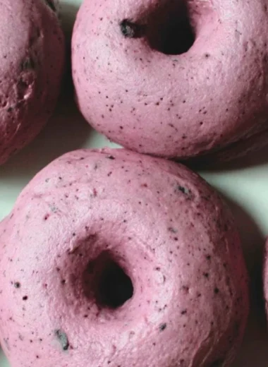 Freshly baked sourdough blueberry bagels on a wooden board.