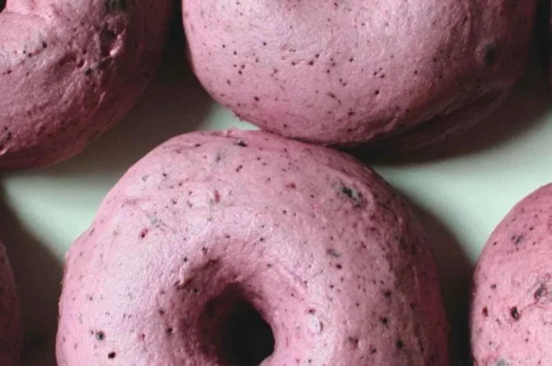 Freshly baked sourdough blueberry bagels on a wooden board.