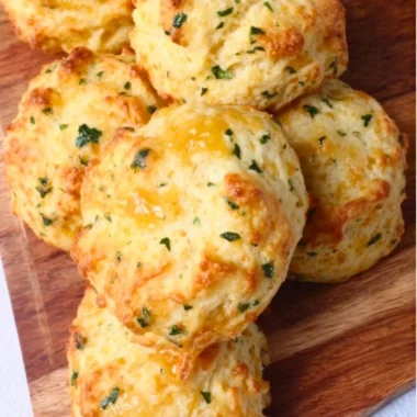 Freshly baked sourdough Greek yogurt cheddar biscuits on a wooden table
