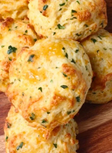 Freshly baked sourdough Greek yogurt cheddar biscuits on a wooden table