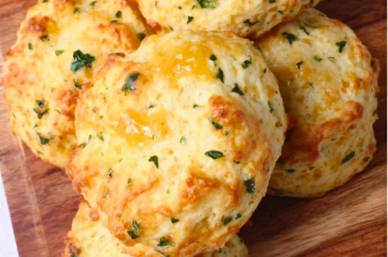 Freshly baked sourdough Greek yogurt cheddar biscuits on a wooden table