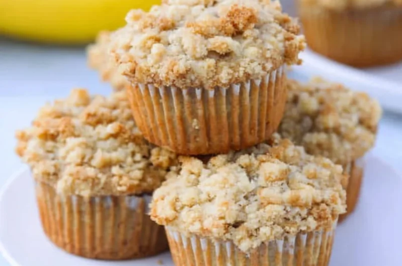 Homemade banana muffins with brown sugar crumb topping on a wooden table