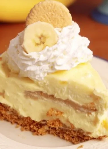 Slice of banana pudding cheesecake garnished with banana slices and whipped cream