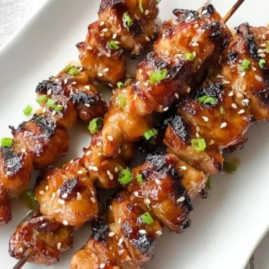 Delicious plate of teriyaki chicken garnished with sesame seeds and green onions.
