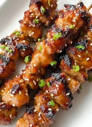 Delicious plate of teriyaki chicken garnished with sesame seeds and green onions.