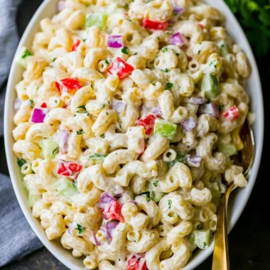 Creamy macaroni salad in a bowl with fresh vegetables and dressing