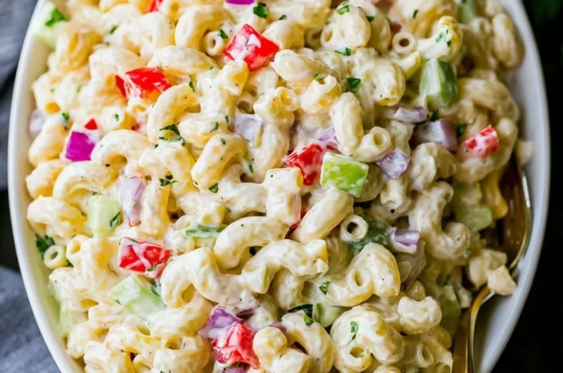 Creamy macaroni salad in a bowl with fresh vegetables and dressing