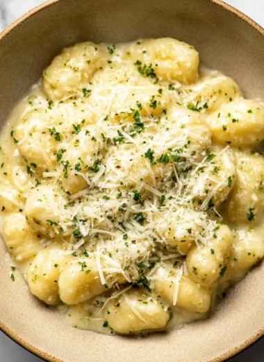 Creamy pesto gnocchi with fresh basil and cheese, served in a bowl.