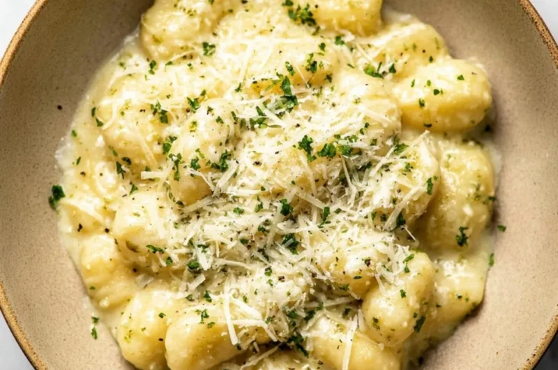 Creamy pesto gnocchi with fresh basil and cheese, served in a bowl.