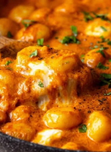Creamy red sauce gnocchi served in a bowl, garnished with herbs and cheese
