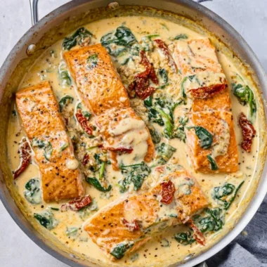 Plate of creamy Tuscan garlic salmon garnished with herbs and served with vegetables.