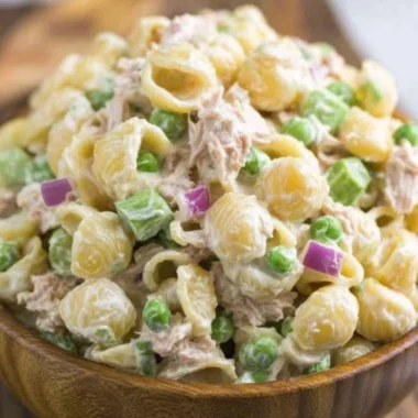 A bowl of fresh Tuna Pasta Salad topped with vegetables and herbs