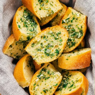 Freshly baked Vegan Garlic Bread with herbs and garlic on a wooden cutting board