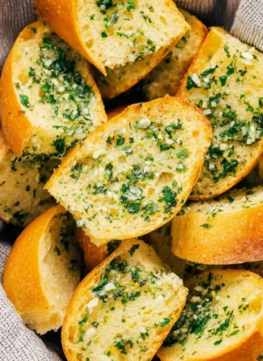 Freshly baked Vegan Garlic Bread with herbs and garlic on a wooden cutting board