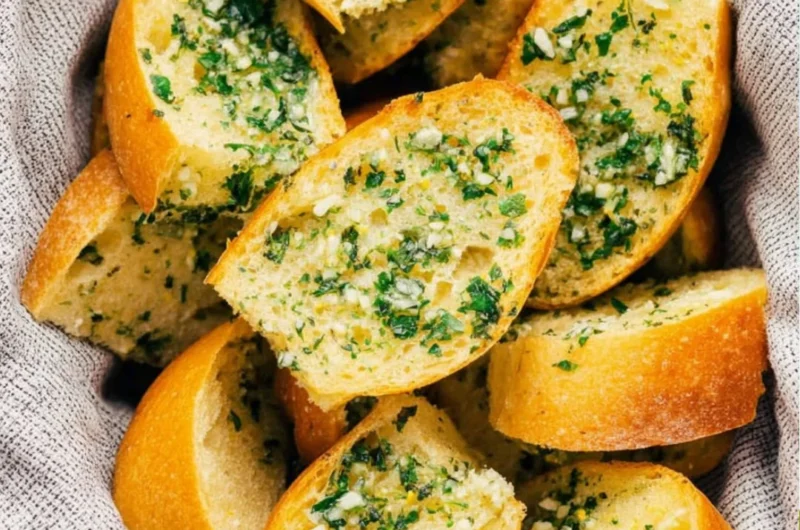 Freshly baked Vegan Garlic Bread with herbs and garlic on a wooden cutting board