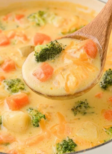 A bowl of creamy vegetable soup garnished with fresh herbs and vegetables.