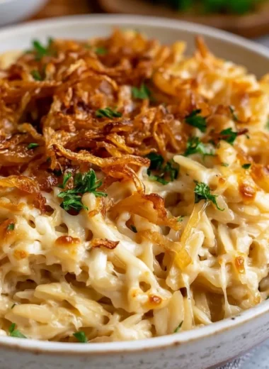 Baked French Onion Orzo topped with melted cheese in a casserole dish