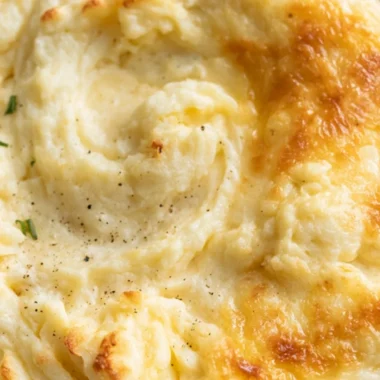 Creamy baked mashed potatoes in a casserole dish topped with golden brown cheese