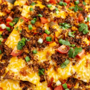 Cozy air fryer nachos topped with cheese, jalapeños, and fresh veggies.