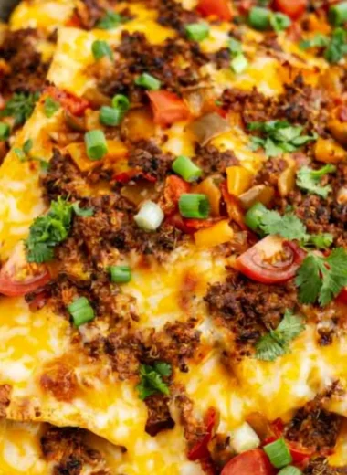 Cozy air fryer nachos topped with cheese, jalapeños, and fresh veggies.