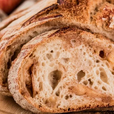Freshly baked cozy apple cider sourdough loaf on a wooden table