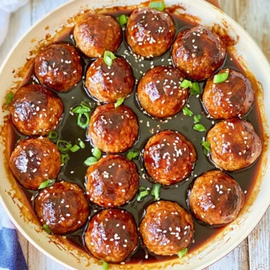 Delicious Asian glazed meatballs served with a vibrant sauce and garnished.