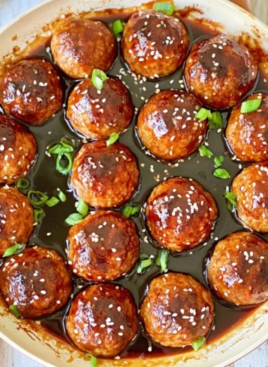 Delicious Asian glazed meatballs served with a vibrant sauce and garnished.