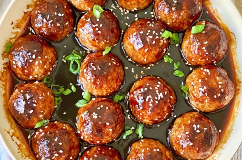 Delicious Asian glazed meatballs served with a vibrant sauce and garnished.