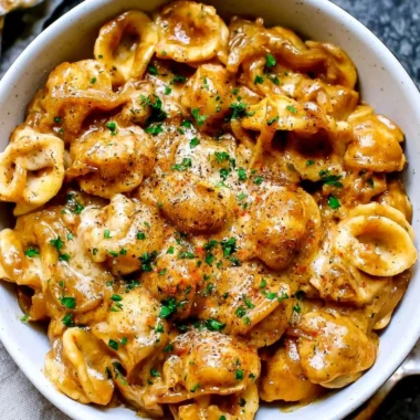 Creamy French onion pasta served in a cozy bowl with melted cheese on top.