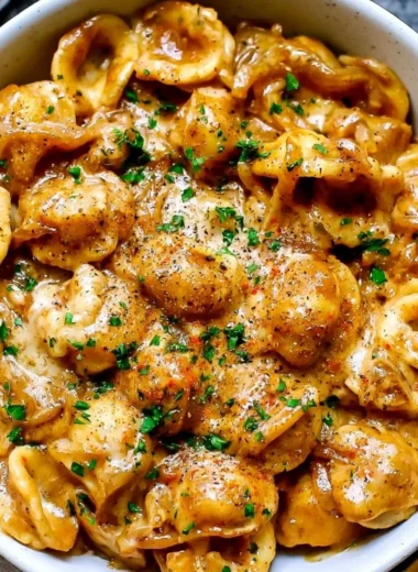 Creamy French onion pasta served in a cozy bowl with melted cheese on top.