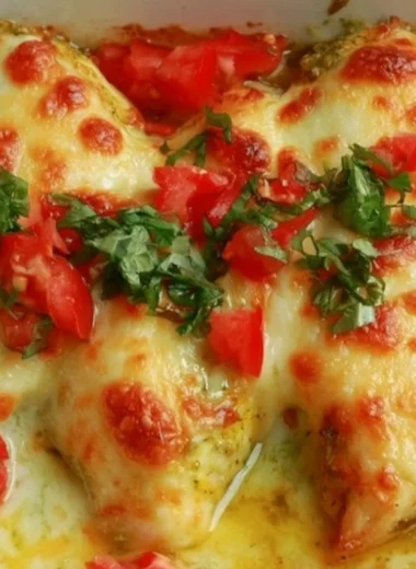 Delicious creamy pesto baked chicken served on a plate with herbs.