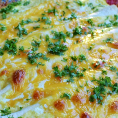 Overnight breakfast burrito casserole topped with cheese and fresh herbs