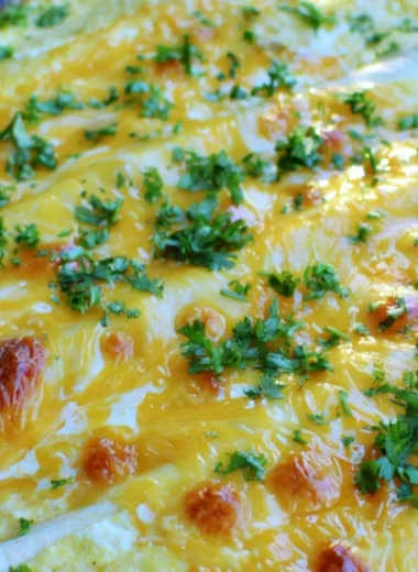 Overnight breakfast burrito casserole topped with cheese and fresh herbs