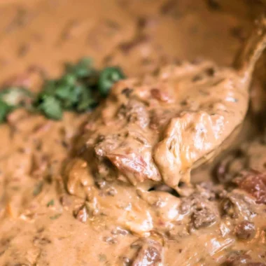 Slow cooker queso dip with melted cheese and toppings in a bowl
