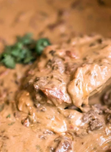 Slow cooker queso dip with melted cheese and toppings in a bowl
