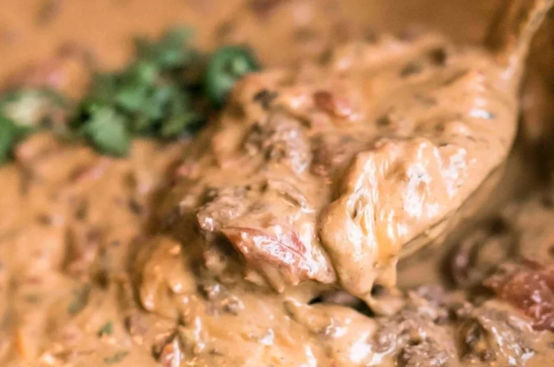 Slow cooker queso dip with melted cheese and toppings in a bowl