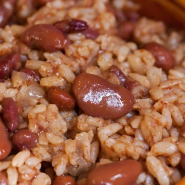 Bowl of cozy red beans and rice served with fresh herbs for a comforting meal.