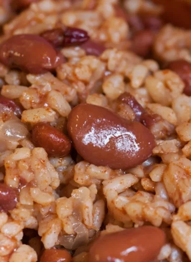 Bowl of cozy red beans and rice served with fresh herbs for a comforting meal.