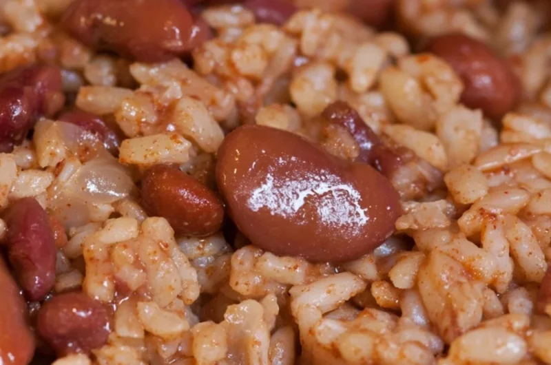 Bowl of cozy red beans and rice served with fresh herbs for a comforting meal.