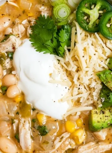 A hearty bowl of cozy white bean chili garnished with parsley and served with crusty bread.