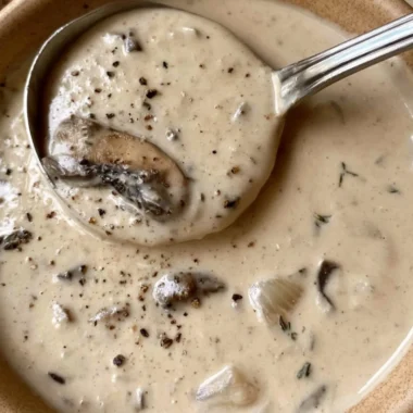 Bowl of creamy mushroom soup garnished with fresh herbs