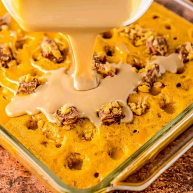 Deliciously moist Pumpkin Spice Poke Cake topped with whipped cream and spices.
