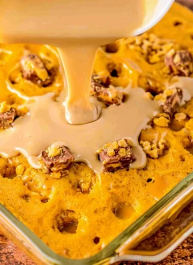 Deliciously moist Pumpkin Spice Poke Cake topped with whipped cream and spices.